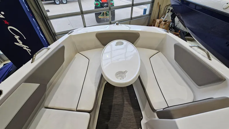 Slide: The Image of 2022 Glastron GTD 180 boat interior with seating and table in a showroom. - 14