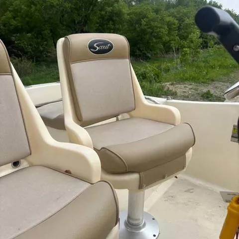 Slide: The Image of 2014 Scout 175 Sportfish boat seats with beige upholstery and logo, surrounded by greenery. - 7