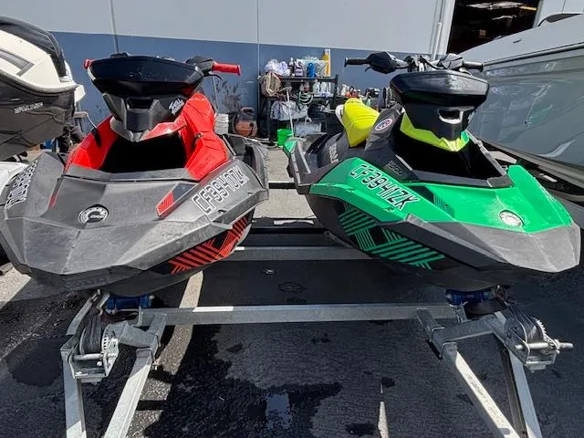 The Image of 2021 Sea-Doo SPARK TRIXX 3up jet skis in red and green on a trailer. - 0