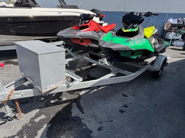 Slide: The Image of Two 2021 Sea-Doo SPARK TRIXX 3up jet skis on a trailer in a parking area. - 2