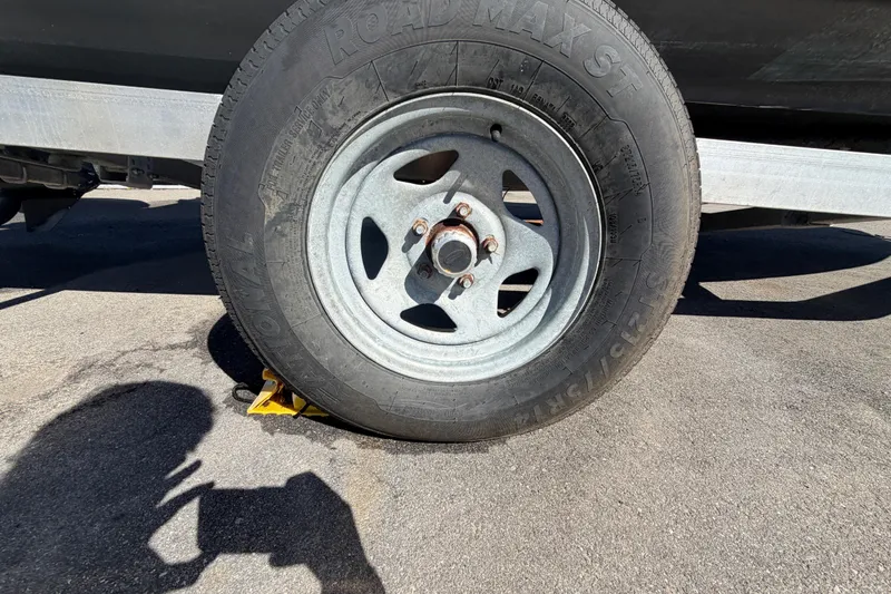 Slide: The Image of Trailer wheel of a 2008 Sea Fox 216 Dual Console, secured with a yellow wheel chock. - 53