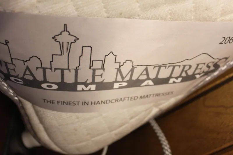 Slide: The Image of Seattle Mattress Company label on handcrafted mattress, featuring city skyline design. - 19