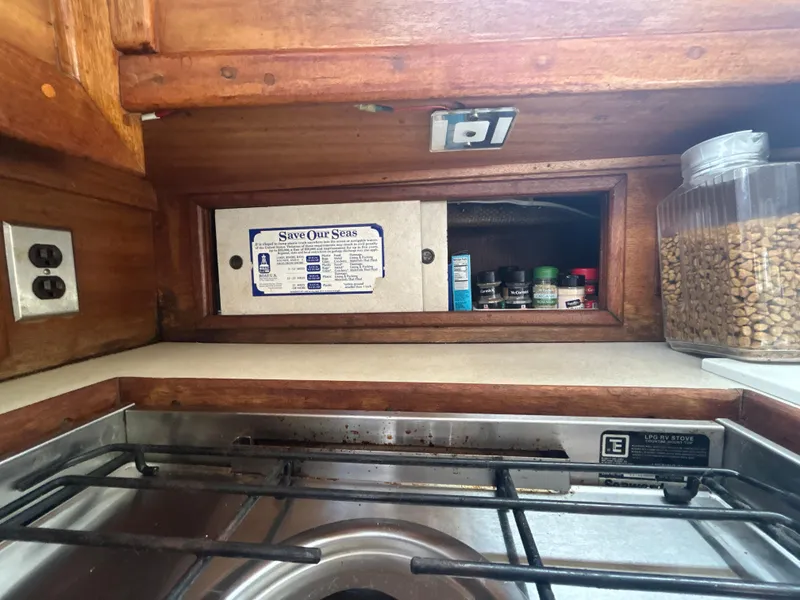 Slide: The Image of 1973 Challenger Cruiser kitchen with wooden cabinets, spices, and a stove. - 22