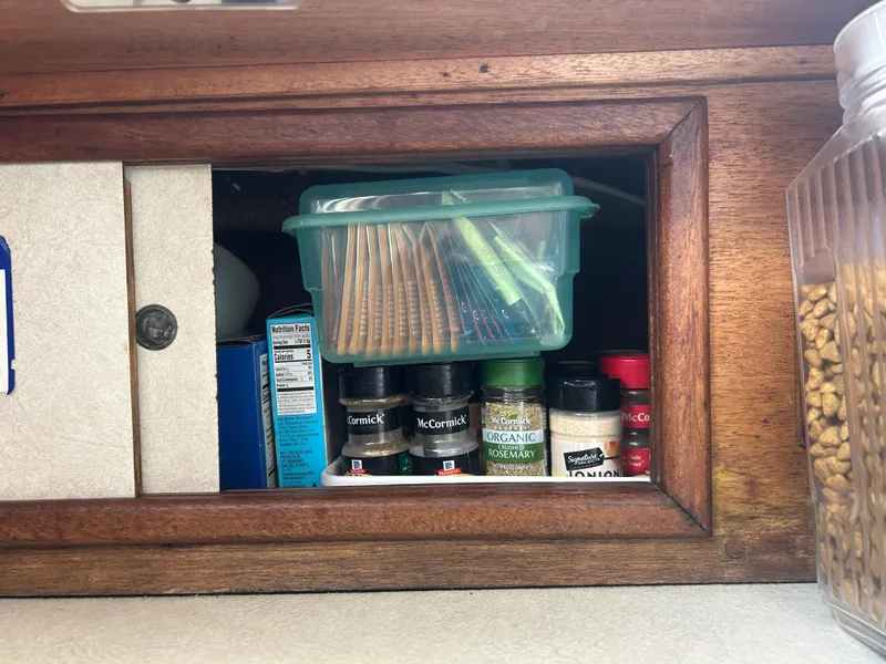 Slide: The Image of Wooden cabinet with spices and a plastic container, inside a 1973 Challenger Cruiser. - 24