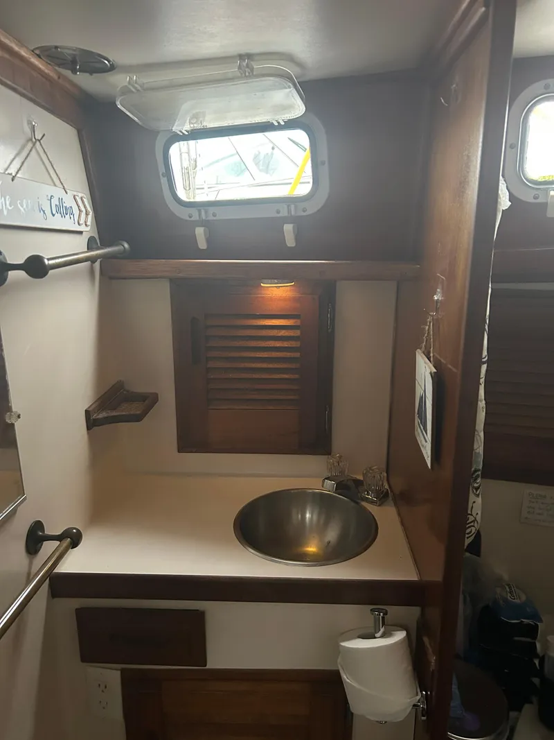 Slide: The Image of 1973 Challenger Cruiser bathroom with sink, wooden accents, and porthole window. - 39