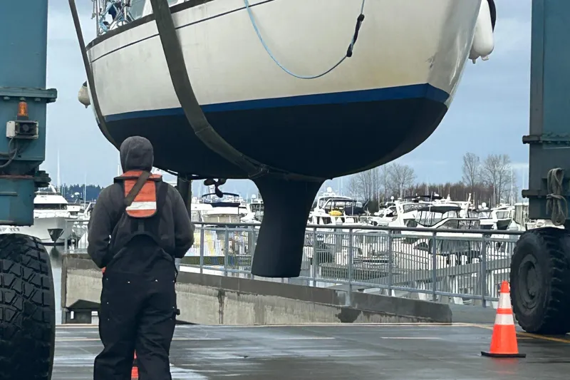 Slide: The Image of A 1973 Challenger Cruiser sailboat being lifted at a marina with a worker nearby. - 5