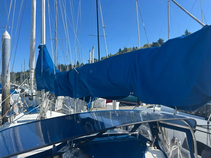 Slide: The Image of 1973 Challenger Cruiser sailboat with blue cover docked at marina under clear sky. - 9
