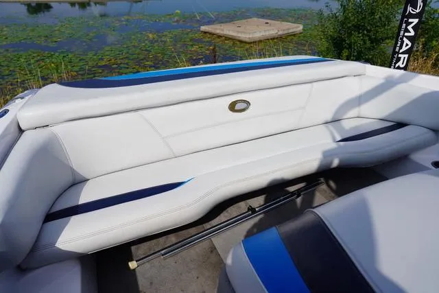 Slide: The Image of 2004 Supra COMP LTS/SK boat interior with white and blue seating by a lake. - 22