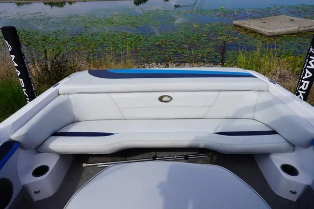 Slide: The Image of 2004 Supra COMP LTS/SK boat interior with white seating, near a lily pad-covered water body. - 23