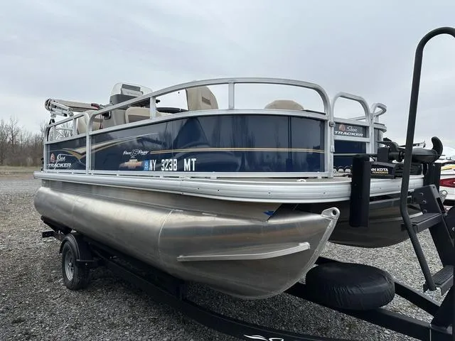 Slide: The Image of 2023 Sun Tracker Bass Buggy® 16 XL Select pontoon boat on trailer, parked outdoors. - 4