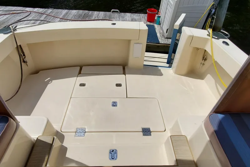 Slide: The Image of 2006 Mainship 34 Rum Runner Classic boat deck with storage compartments and dockside view. - 14