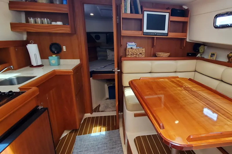 Slide: The Image of 2006 Mainship 34 Rum Runner Classic interior with dining area, kitchenette, and cozy seating. - 16