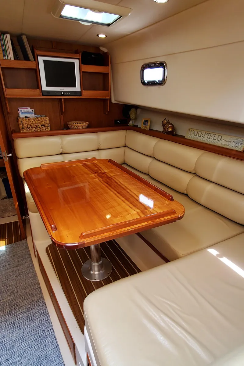 Slide: The Image of 2006 Mainship 34 Rum Runner Classic interior with cozy seating and wooden table. - 19