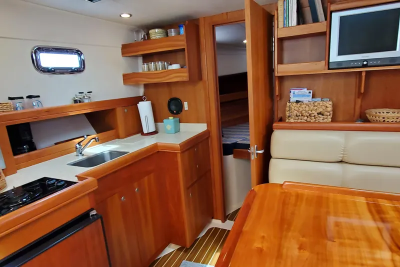 Slide: The Image of 2006 Mainship 34 Rum Runner classic yacht interior with kitchen, seating, and wooden cabinetry. - 21