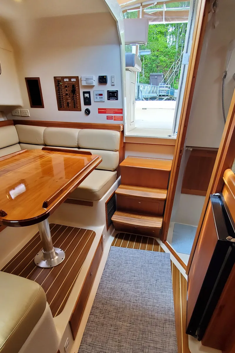 Slide: The Image of Interior of 2006 Mainship 34 Rum Runner Classic with wooden table and seating area. - 27