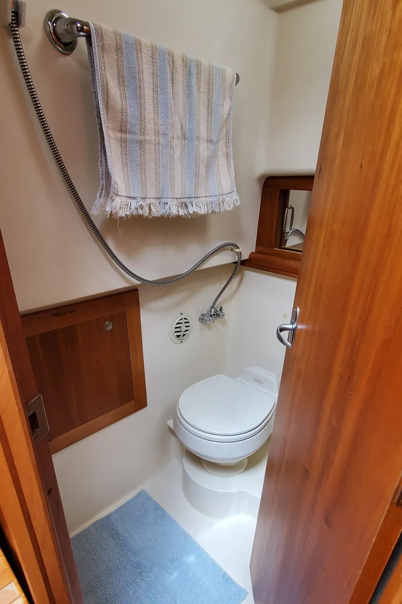 Slide: The Image of 2006 Mainship 34 Rum Runner classic boat bathroom with toilet, towel, and wooden accents. - 28