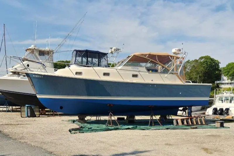Slide: The Image of 2006 Mainship 34 Rum Runner Classic boat on dry dock, blue and white exterior. - 39