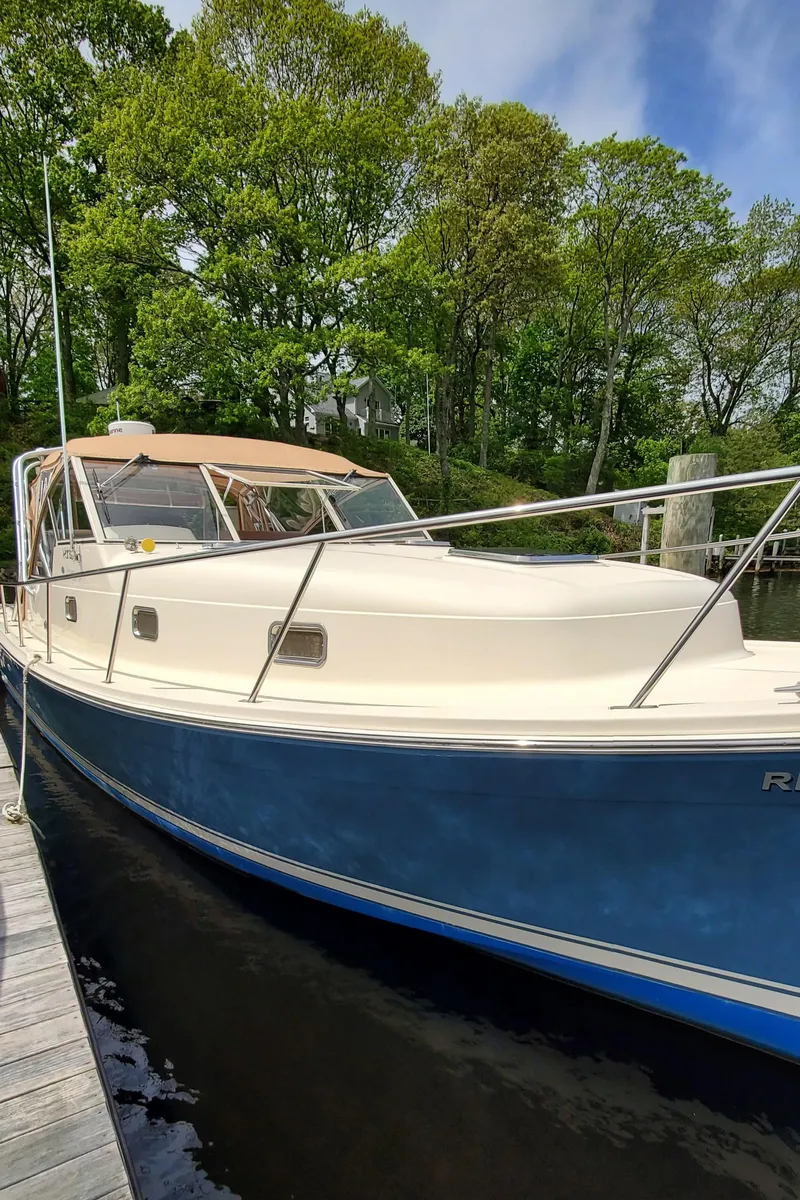 Slide: The Image of 2006 Mainship 34 Rum Runner Classic boat docked by lush greenery. - 4