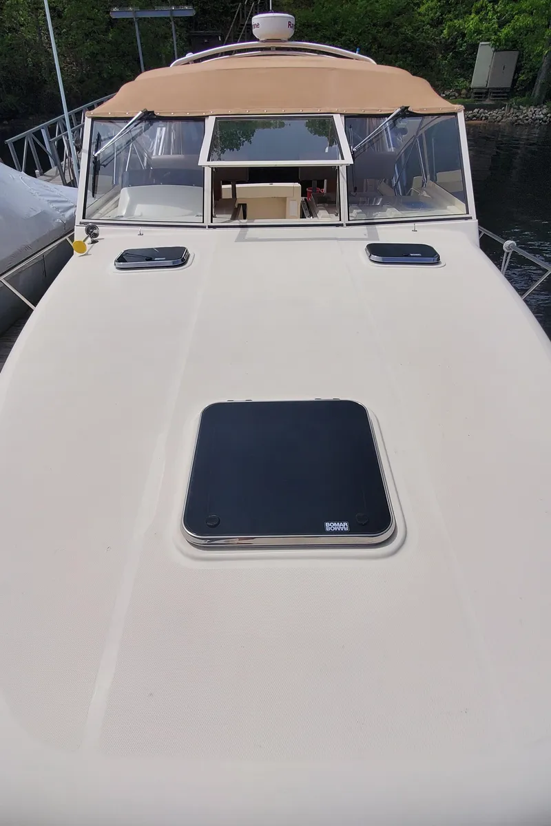 Slide: The Image of 2006 Mainship 34 Rum Runner Classic boat with tan canopy and deck hatches. - 7