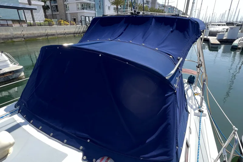 Slide: The Image of 2005 Hunter 33 sailboat with blue canvas cover docked in marina. - 3