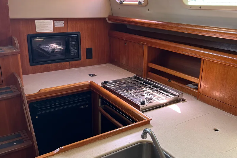Slide: The Image of Compact kitchen area in a 2005 Hunter 33 sailboat with stove, microwave, and storage. - 5