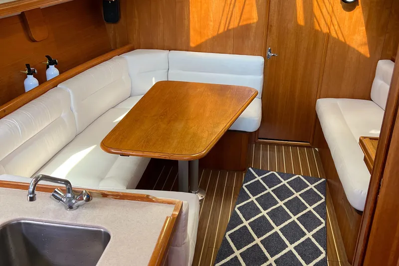 Slide: The Image of Interior of 2005 Hunter 33 sailboat with wooden table, white seating, and kitchenette. - 6