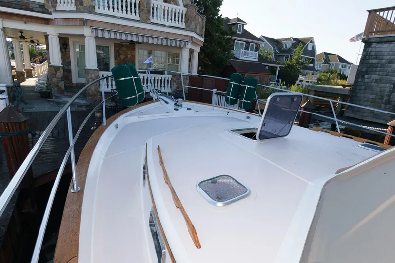Slide: The Image of 2000 Sabreline 47 Motor Yacht deck with open hatch and residential backdrop. - 14