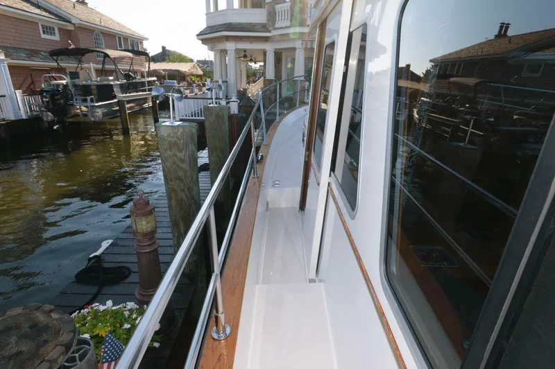 Slide: The Image of Sabreline 47 Motor Yacht 2000 docked near waterfront homes, showcasing sleek design and polished railings. - 19