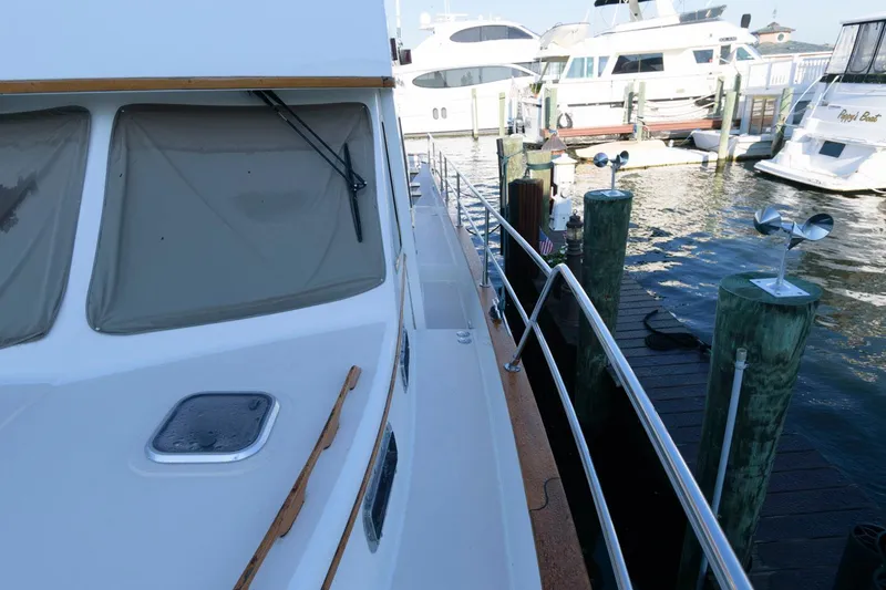 Slide: The Image of 2000 Sabreline 47 Motor Yacht docked at marina, side view with railing and nearby boats. - 20