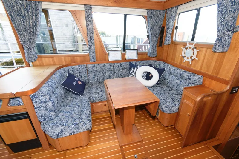 Slide: The Image of Interior of 2000 Sabreline 47 Motor Yacht with wooden dining area and blue patterned seating. - 22