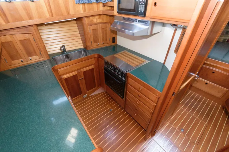 Slide: The Image of 2000 Sabreline 47 Motor Yacht kitchen with wood cabinetry, green countertops, and modern appliances. - 31