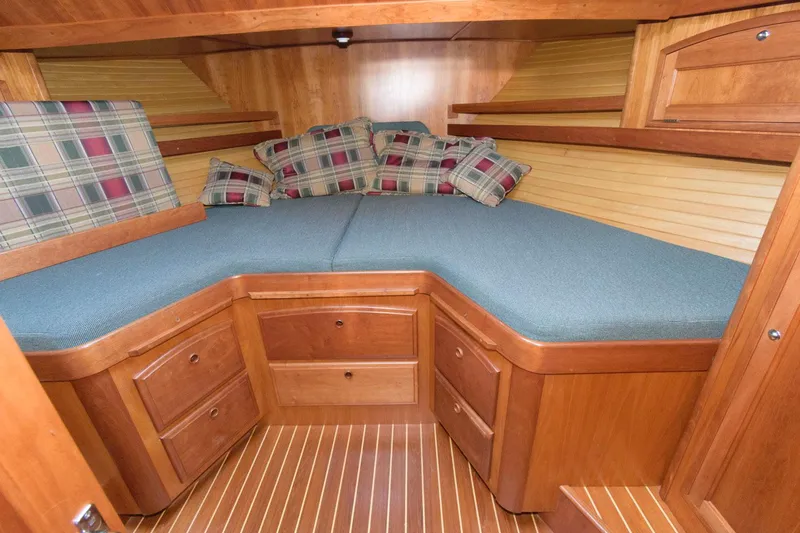 Slide: The Image of 2000 Sabreline 47 Motor Yacht cabin with wood finish, blue cushions, and plaid pillows. - 36
