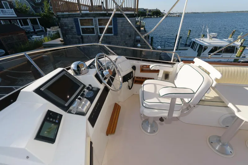 Slide: The Image of 2000 Sabreline 47 Motor Yacht helm with steering wheel, controls, and seating, overlooking marina. - 6
