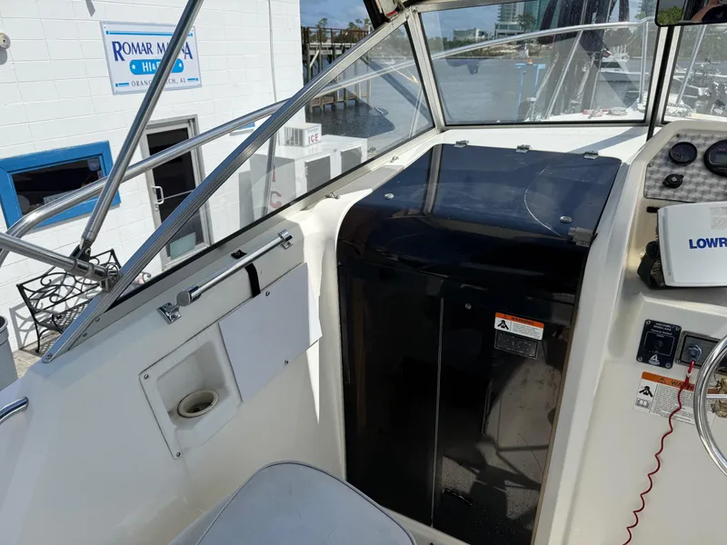 Slide: The Image of 2004 Aquasport 250 Explorer boat cockpit with navigation equipment and marina view. - 14