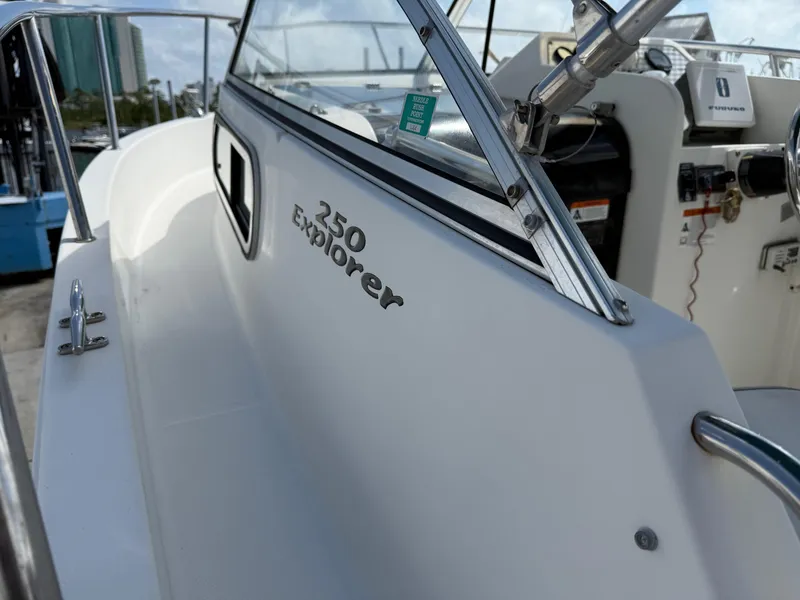 Slide: The Image of 2004 Aquasport 250 Explorer boat, white exterior, docked with visible controls and railing. - 17
