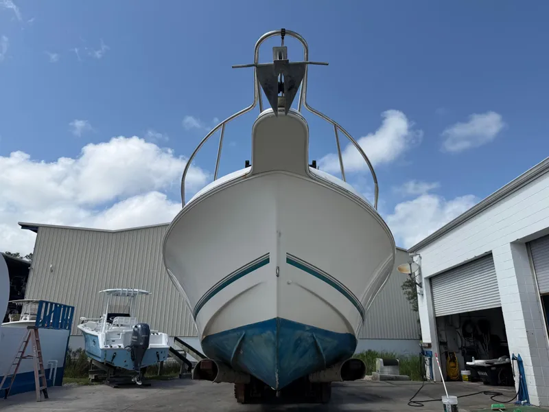 Slide: The Image of 2004 Aquasport 250 Explorer boat in a shipyard, viewed from the front under a clear sky. - 2