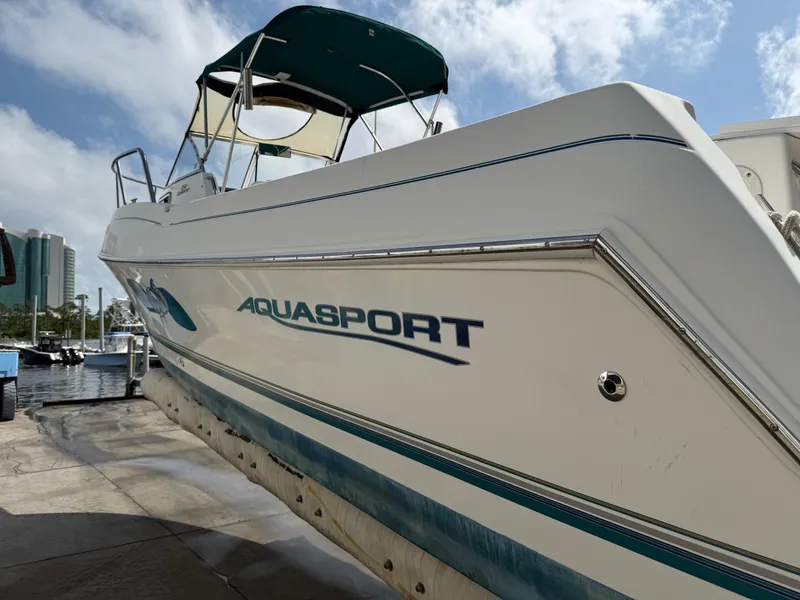 Slide: The Image of 2004 Aquasport 250 Explorer boat docked under a partly cloudy sky. - 8