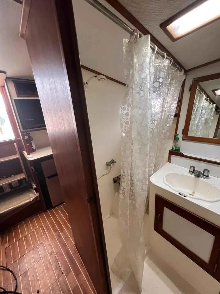 Slide: The Image of 1988 Topaz 37 Sportfisherman bathroom with shower, sink, and wooden accents. - 5