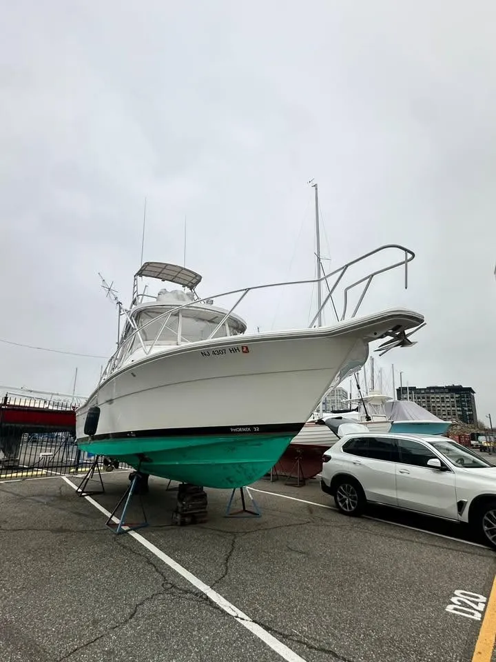 The Image of 1997 Phoenix 32 Tournament boat on display in a parking lot. - 0
