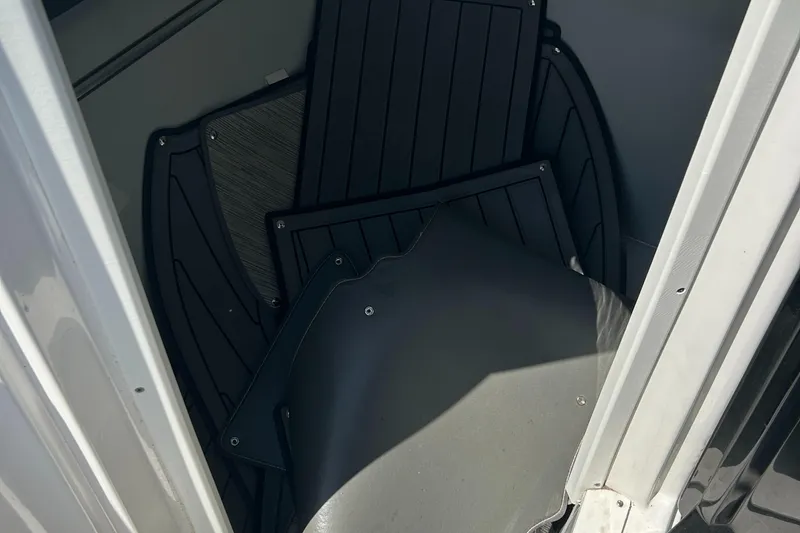 Slide: The Image of 2018 Rinker 26QX BR boat interior storage compartment with black panels. - 4