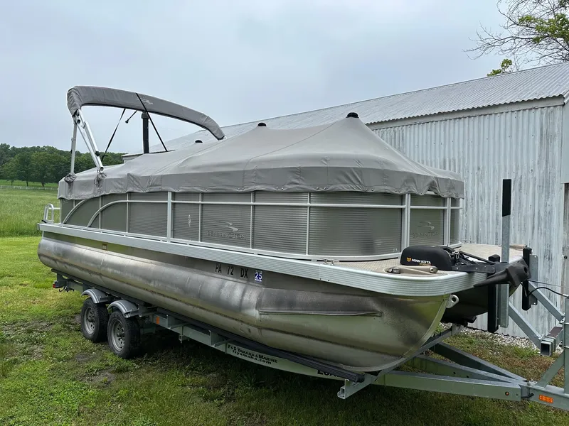 Slide: The Image of 2019 Bennington 22 SSR Quad Bench pontoon boat on trailer, covered and parked outdoors. - 1
