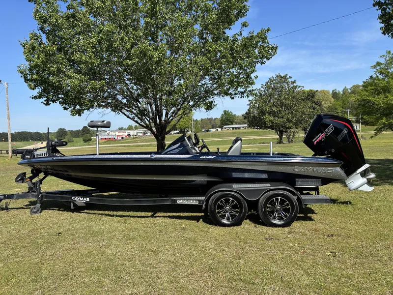 Slide: The Image of 2022 Caymas CX21 Pro boat on trailer, parked on grass with trees in background. - 1