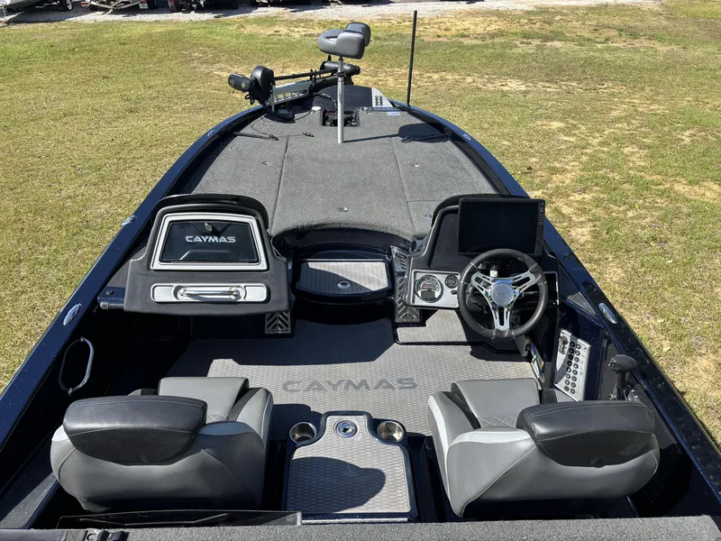 Slide: The Image of 2022 Caymas CX21 Pro boat interior with steering wheel and seating on grassy area. - 7