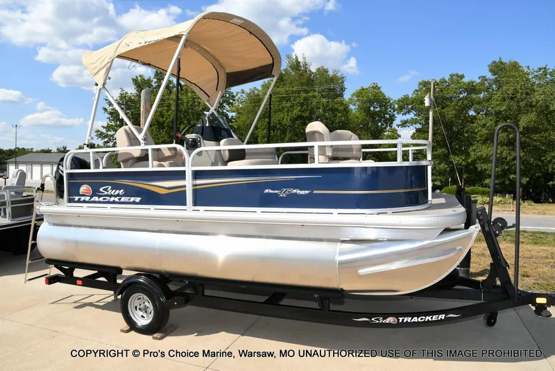 Slide: The Image of 2025 Sun Tracker Bass Buggy 16 XL Select pontoon boat on trailer, outdoors. - 42
