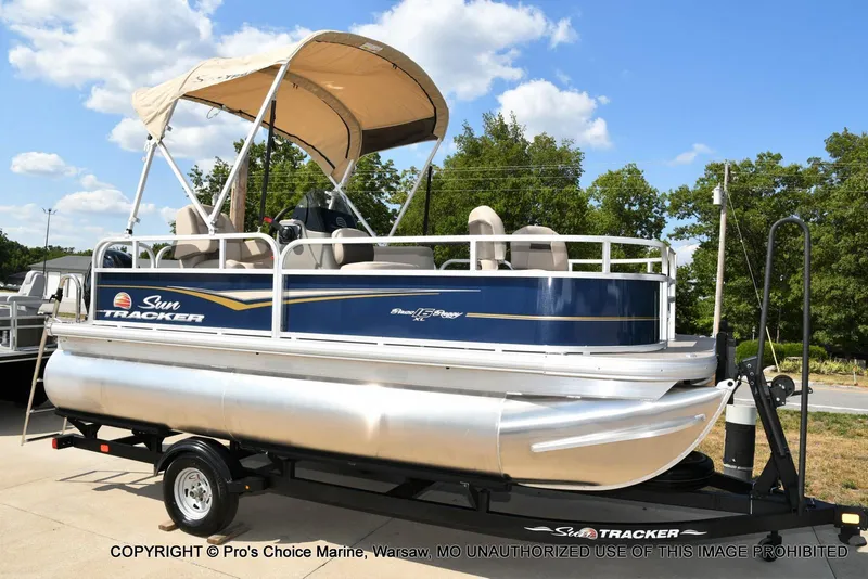 Slide: The Image of 2025 Sun Tracker Bass Buggy 16 XL Select pontoon boat on trailer, sunny day. - 44