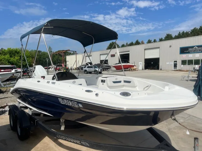 Slide: The Image of 2022 Hurricane SS 185 boat with canopy on trailer, parked outside a marina. - 1