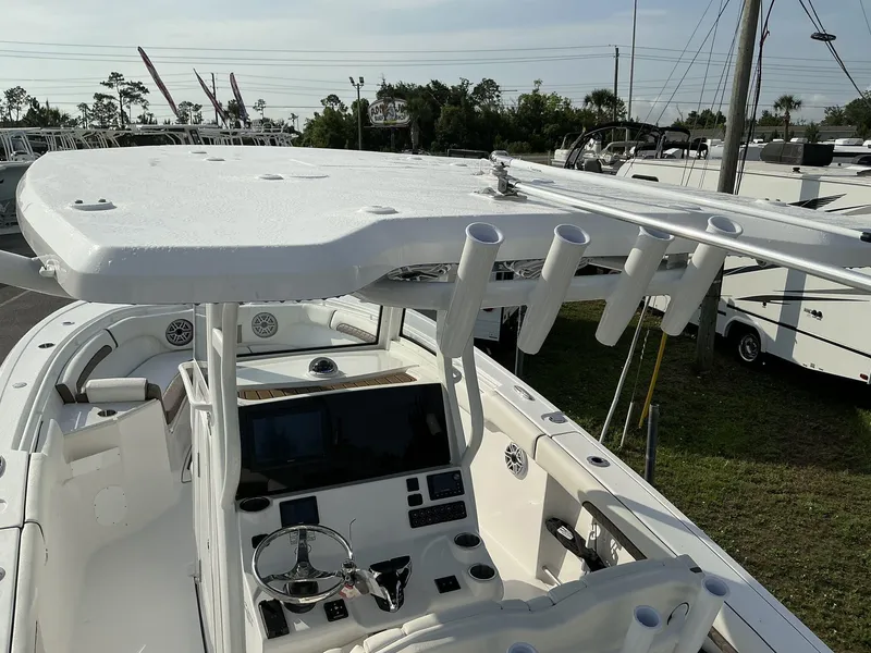 Slide: The Image of 2025 Tidewater 282CC boat cockpit with steering wheel and rod holders, parked outdoors. - 11