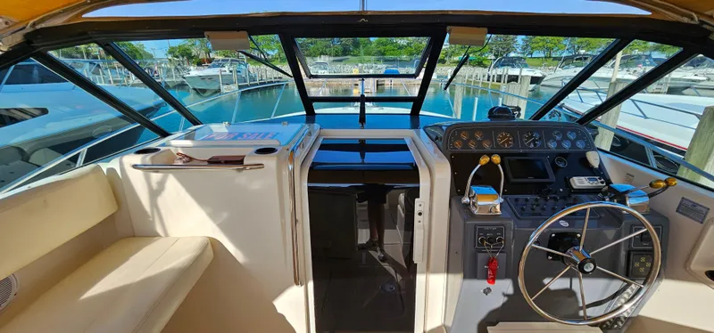 Slide: The Image of 1994 Tiara Yachts 3100 Open cockpit with steering wheel and dashboard, docked at marina. - 16