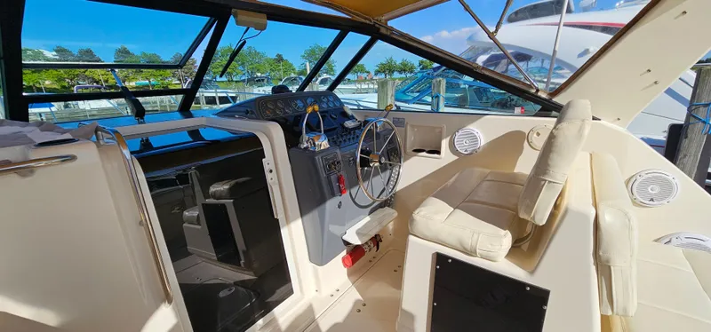 Slide: The Image of 1994 Tiara Yachts 3100 Open cockpit with steering wheel and seating, docked under clear skies. - 19