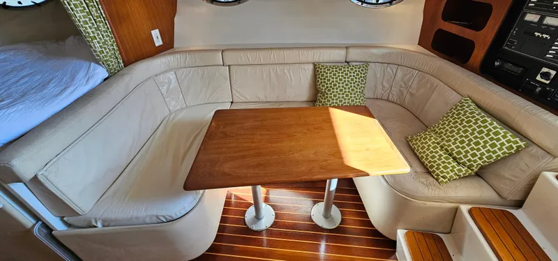 Slide: The Image of 1994 Tiara Yachts 3100 Open interior with beige seating, wooden table, and green cushions. - 32